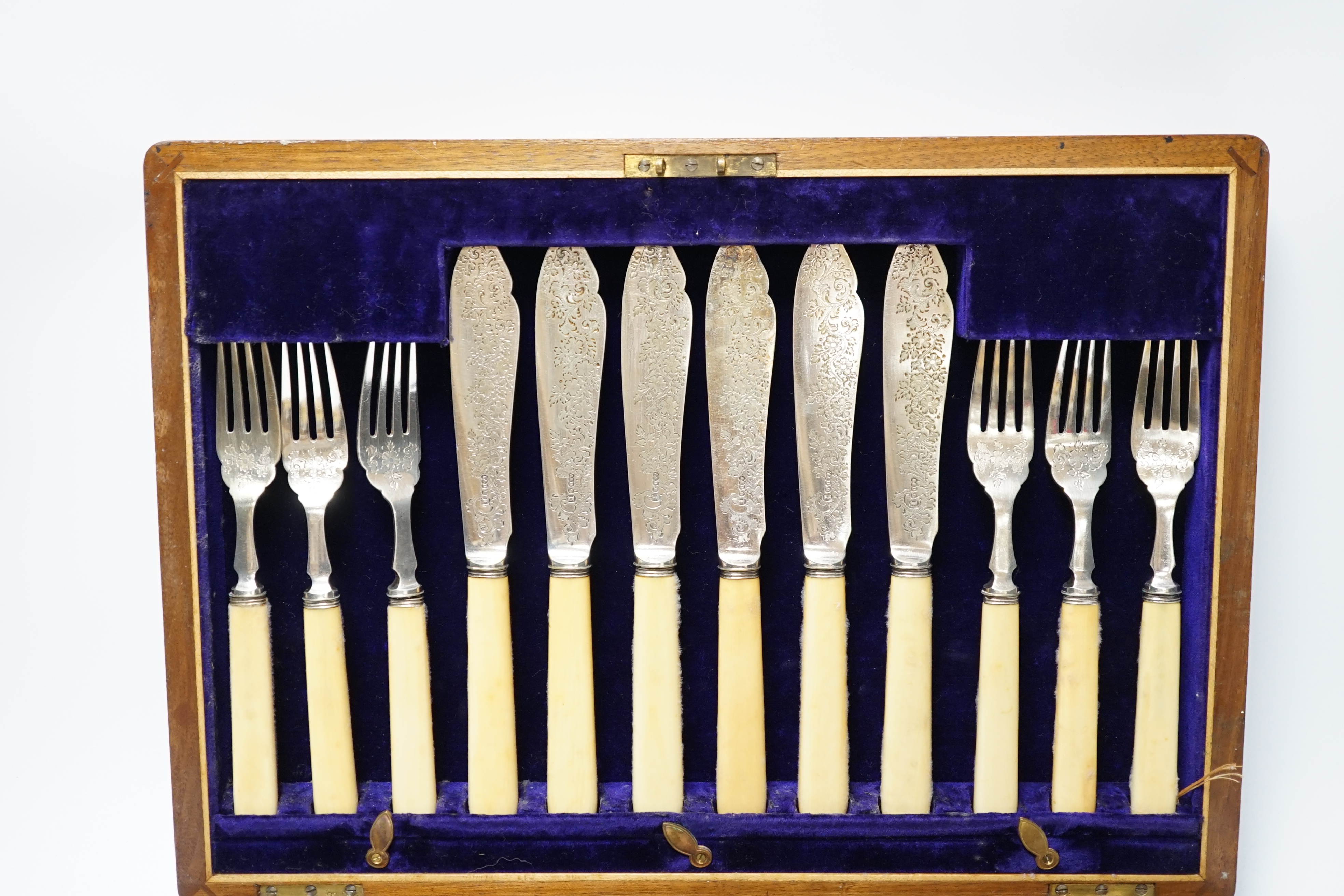 A set of twelve plated engraved fish knives and forks, with bone handles, cased together with a pair of plated fish servers with ivorine handles